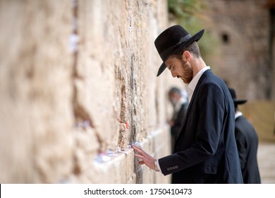 The Western Wall Jerusalem, Israel. April 25, 2018. A Jewish Orthodox Judaism Man With A Black Touching The Wailing Wall With His Hands To Pray.