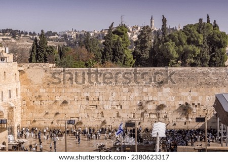 The Western Wall (Wailing Wall), the Judaism shrine, with Jewish worshippers, in Old Town of Jerusalem, Israel, with Mount of Olive in the background.