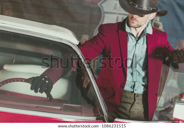 Western Wear Cowboy\
Driver. Caucasian Men and His Classic Vintage Car. American\
Transportation Theme.