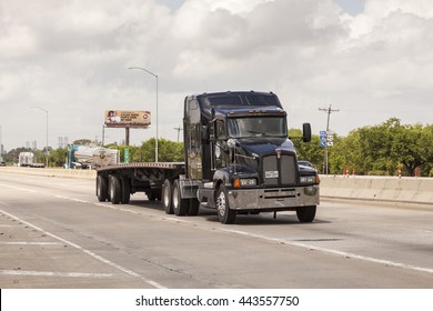 WESTLAKE, USA - APR 15, 2016: Black Kenworth T-660 semitrailer truck with a flatbed trailer on the highway. Louisiana, United States