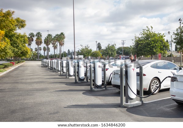 Westminster, California,\
United States - 01-22-2020: A wide shot of several Tesla cars\
parked in a Tesla Supercharger pump station at the Westminster Mall\
parking lot.