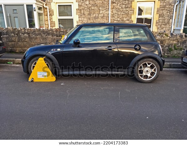 WESTON-SUPER-MARE, UK - JANUARY 5, 2022: A car which has\
been wheel clamped by the Driver and Vehicle Licensing Agency\
because of unpaid vehicle tax.\
