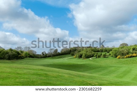 Westwood public parkland shared by golfers (not in this scene) and flanked by trees and shrubs under bright blue sky with clouds in Beverley, Yorkshire, UK.