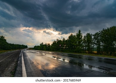 wet asphalt road panorama in countryside on rainy summer day. autumn rain road puddle in forest under dramatic cloudy sky - Shutterstock ID 2017685969