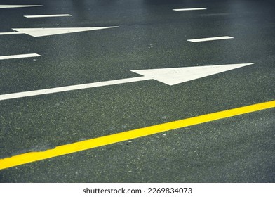 Wet asphalt road with yellow lines and white arrows.