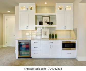 Wet bar with white cabinets fitted with a glass door beverage fridge, granite counter top featuring taupe subway tiles with a glossy finish.
Northwest, USA