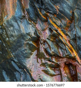 Wet blue slate rock texture, with reddish rust grit