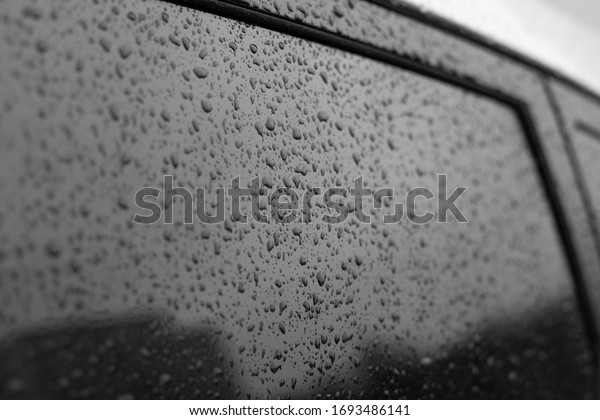 Wet car glass with frame. Black glass surface with\
raindrops. Natural texture of rain drops on glass, backdrop\
background for design