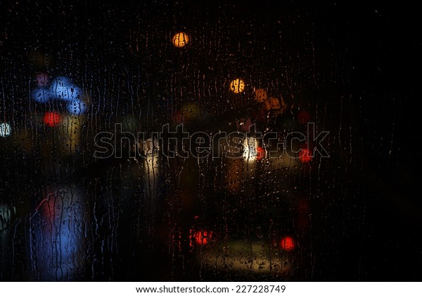 Wet the car window with the background of the night
city traffic view.