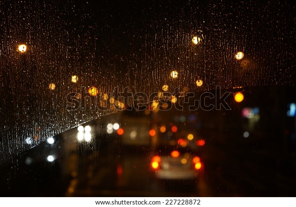 Wet the car window with the background of the night\
city traffic view.