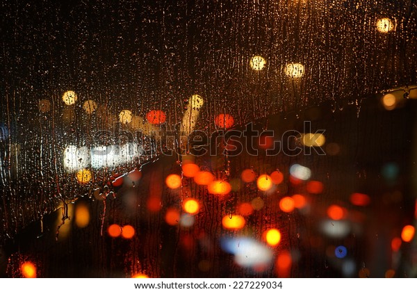 Wet the car window with the background of the night\
city traffic view.