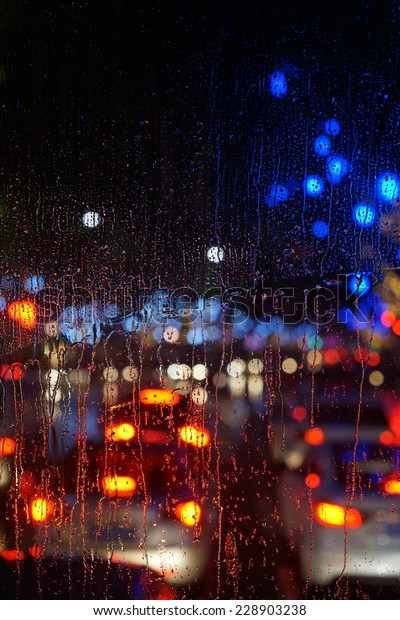 Wet the car window with the
background of the night city traffic and traffic congestion
concept.
