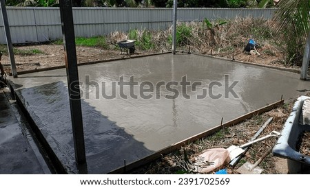 Wet cement on a newly build car garage foundation drying out in the sun inside a residential house compound.