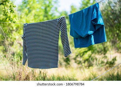 Wet clothes drying on rope between the tents on the green trees background. Camping, tourist life, summer vacation concept.