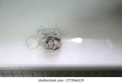 A wet clump of long black hair on a white marble counter top. - Shutterstock ID 1773966119
