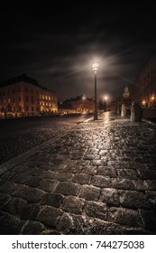 Wet cobblestones reflecting streetlight during autumn night. Stockholm, Sweden