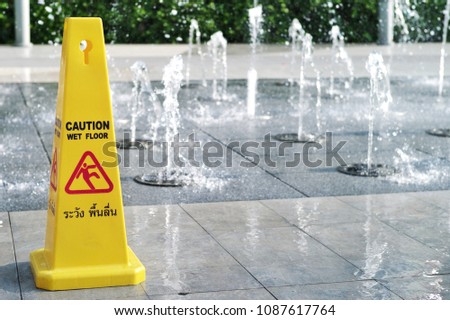 Wet floor caution sign. Warning symbol of slippy floor for pedestrian. Fountain makes wet floor. Thai language means caution wet floor.