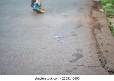 Wet Footprints On A Running Path, With A Runner's Feet Blurred In The Background.