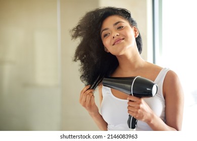 From Wet To Full And Fabulous. Shot Of An Attractive Young Woman Drying Her Hair With A Hairdryer At Home.