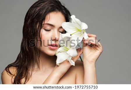 Wet Hair Woman Beauty Face Portrait. Beautiful Model Perfect Skin Make up holding Lily Flower. Brunette Girl Natural Washing Cleaning Cosmetics. Gray Studio Background