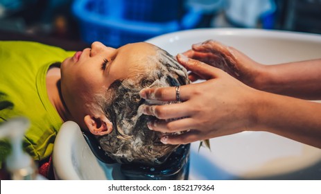 Wet Head White Blond Little Boy Lie Leaning On Over Sink. Woman Female Hands. Hair Wash Massage, Shampoo Foam, Beauty Hairdressing Salon. Hairdresser Work. Child Enjoy Barbershop. Haircut Kid Client