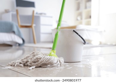 Wet mop with bucket on floor in dorm room, closeup - Powered by Shutterstock