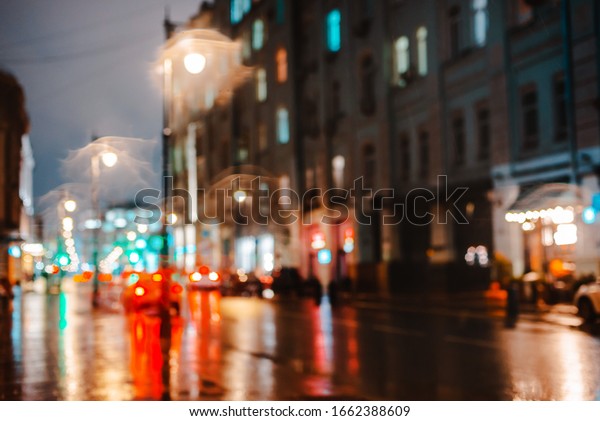 Wet night city street rain Bokeh reflection bright\
colorful lights puddles sidewalk Car headlights lighting reflection\
wet asphalt road Defocused selective focus fuzzy background with\
red lights