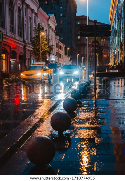 Wet night city street rain Bokeh reflection bright\
colorful lights puddles sidewalk Car headlights lighting reflection\
wet asphalt road Defocused selective focus fuzzy. Russia Moscow 05\
November 2019.