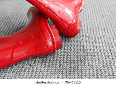 Wet pair of rubber boots on carpet