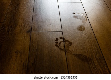 Wet people footprints on dark brown wooden floor and glare from the lightning. Summer holidays and vacations concept.