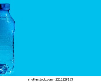 Wet Plastic Bottle Of Water On Blue Background With Place For Text, Logo, Design.