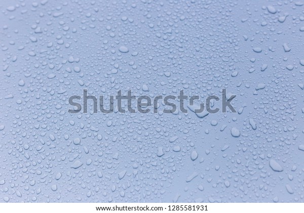 Wet rain drops on silver car hood.\
Abstract background. Water drops on red metal texture. Shallow\
focus, car body. Detail of red wet surface after rain\
