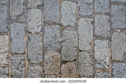 Wet rectangular cobble stone road, texture photographed from above