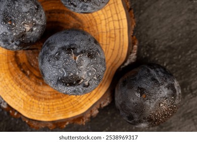 wet ripe purple plum on the table, dark purple plum fruits in drops of water close up - Powered by Shutterstock