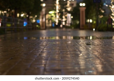 Wet Road Surface And City Lights In The Distance