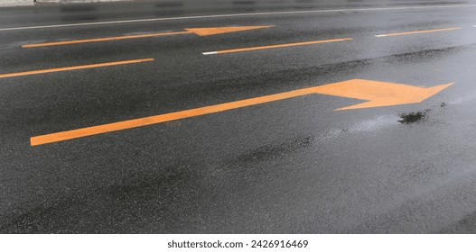 A wet road with yellow arrows on the asphalt