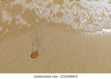 Wet Sand Beach Surface With Tide And Small Brown Stone, Natural Textured Background