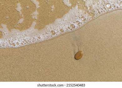 Wet Sand Beach Surface With Tide And Small Brown Stone, Natural Textured Background