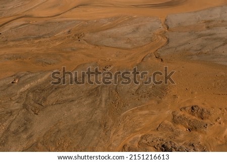 Wet sand and beautiful streaks from the water top view. Natural sand looks as if someone turned over and spilled orange paint. Minimalism background.