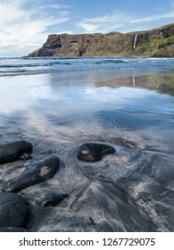 Wet sand, black stones and cliffs, Talisker bay beach, Isle of Skye, Scotland, UK