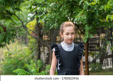 Wet Schoolgirl Standing In The Rain. Girl Wet. Teenager In School Uniform In Spring Or Warm Autumn. Girl 5th Grade. Hair Coloring. Portrait Of A Schoolgirl With Splashes Of Water. Back To School