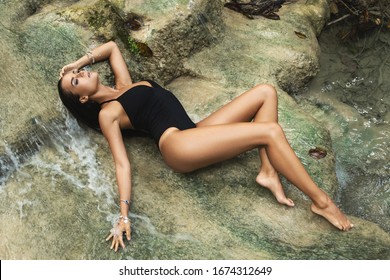 Wet And Sexy Woman Lying In The Water Beside Waterfall