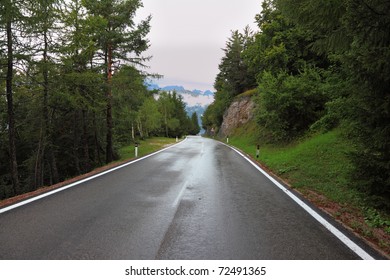 Wet shiny road in the Swiss Alps. Cold autumn day