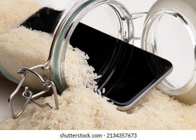 A wet smartphone is dried in rice and glass bottle on white background