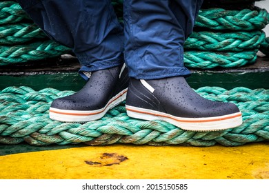 Wet weather boots standing on ropes on a ship
