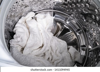 Wet, White towels sit in the basin of a washing machine after a cycle