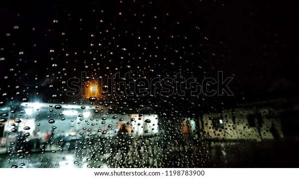 Wet the window with the background of the autumn\
night city. Selective focus.\
