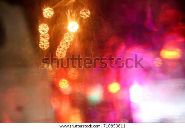 Wet the window with the background of the\
night city traffic view. Drops of rain on glass with colorful light\
bokeh. Abstract background