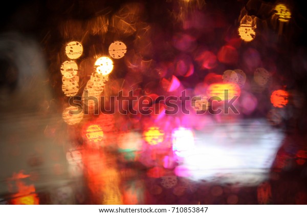 Wet the window with the background of the\
night city traffic view. Drops of rain on glass with colorful light\
bokeh. Abstract background