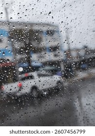 A wet window pane is adorned with countless raindrops, obscuring the world outside in a watery haze.